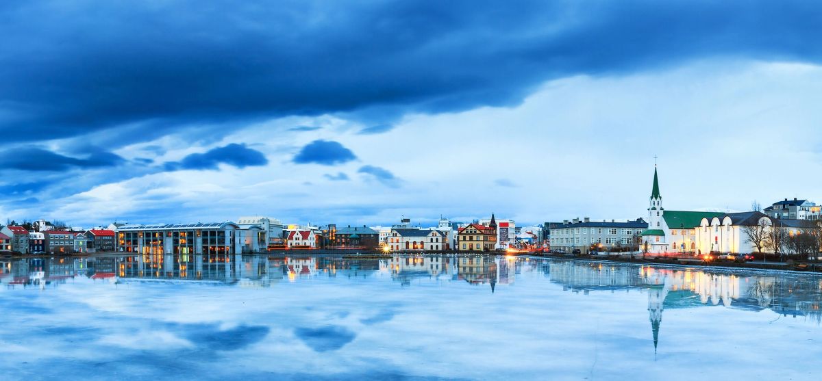 Colourful houses and a church reflected in the still water of Tjörnin pond in central Reykjavík