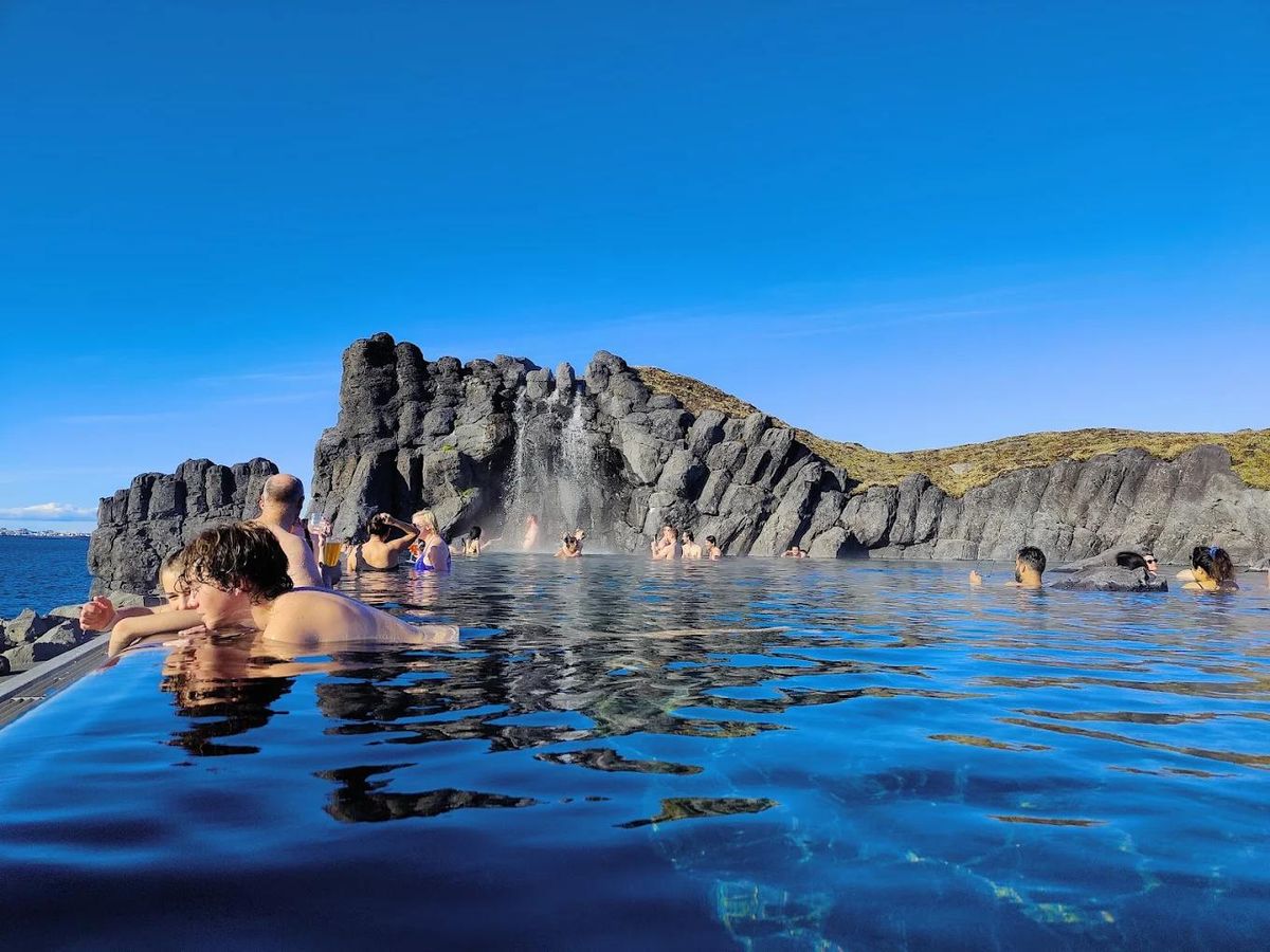 Bathers in the Sky Lagoon infinity pool looking out at the ocean
