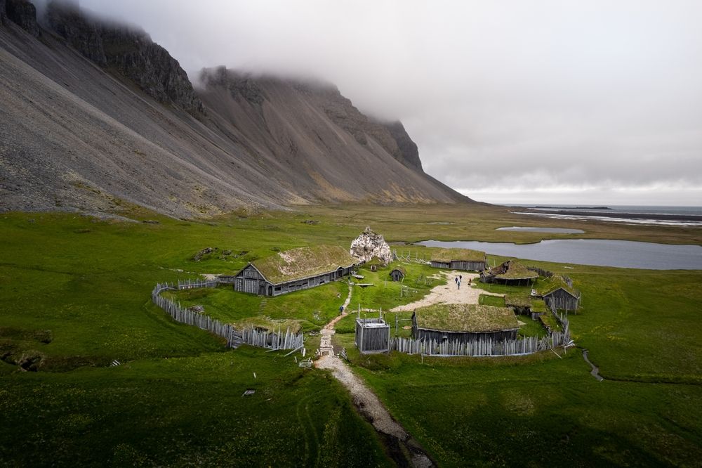 A scenic view of a viking village in Iceland surrounded by rocky hills on cloudy weather