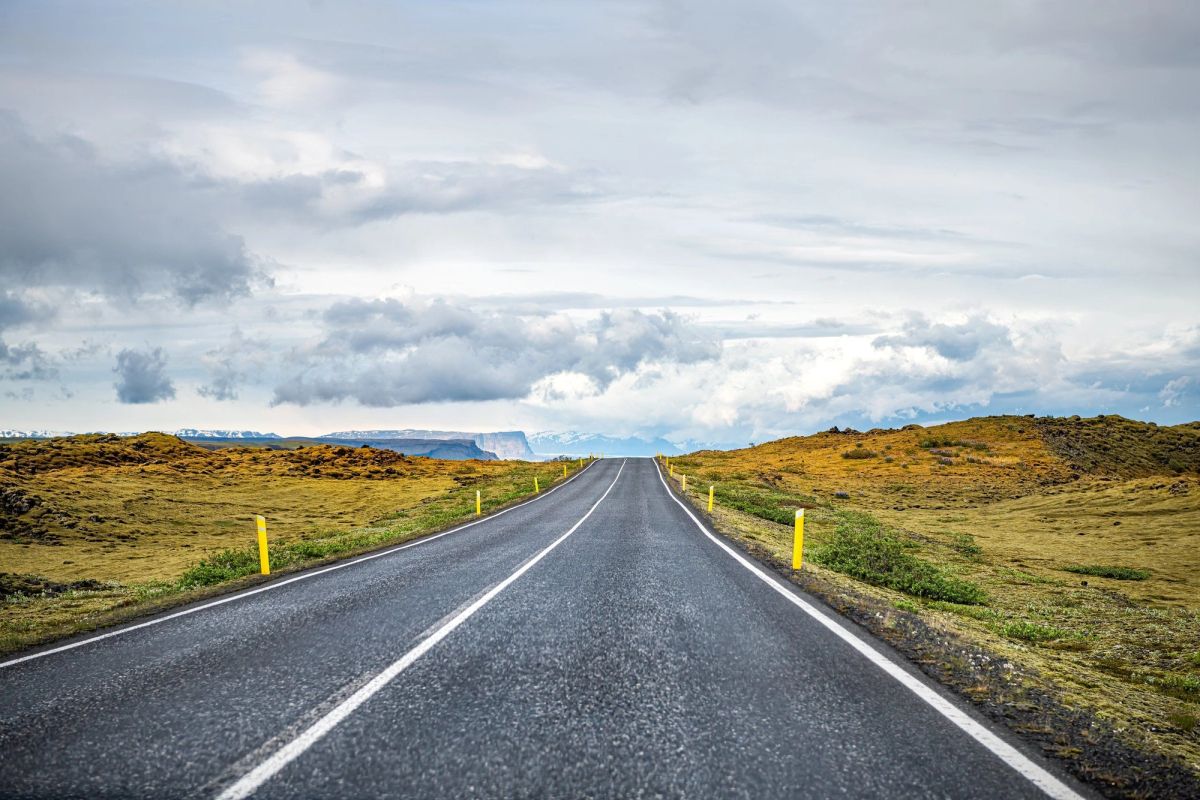 An empty paved two-lane road running through open Icelandic countryside
