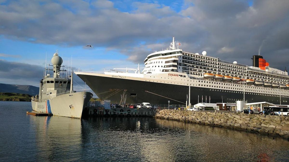 A cruise ship docked at an Icelandic port with mountains behind