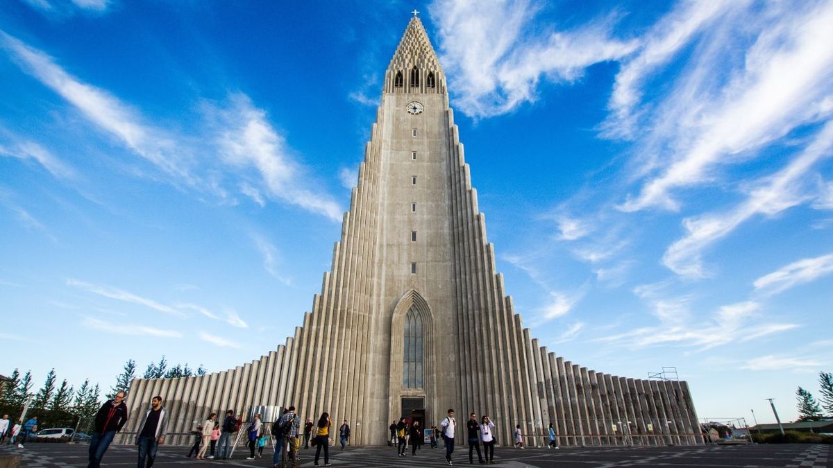 Hallgrímskirkja church with its tall stepped concrete tower under a blue sky, with visitors in front