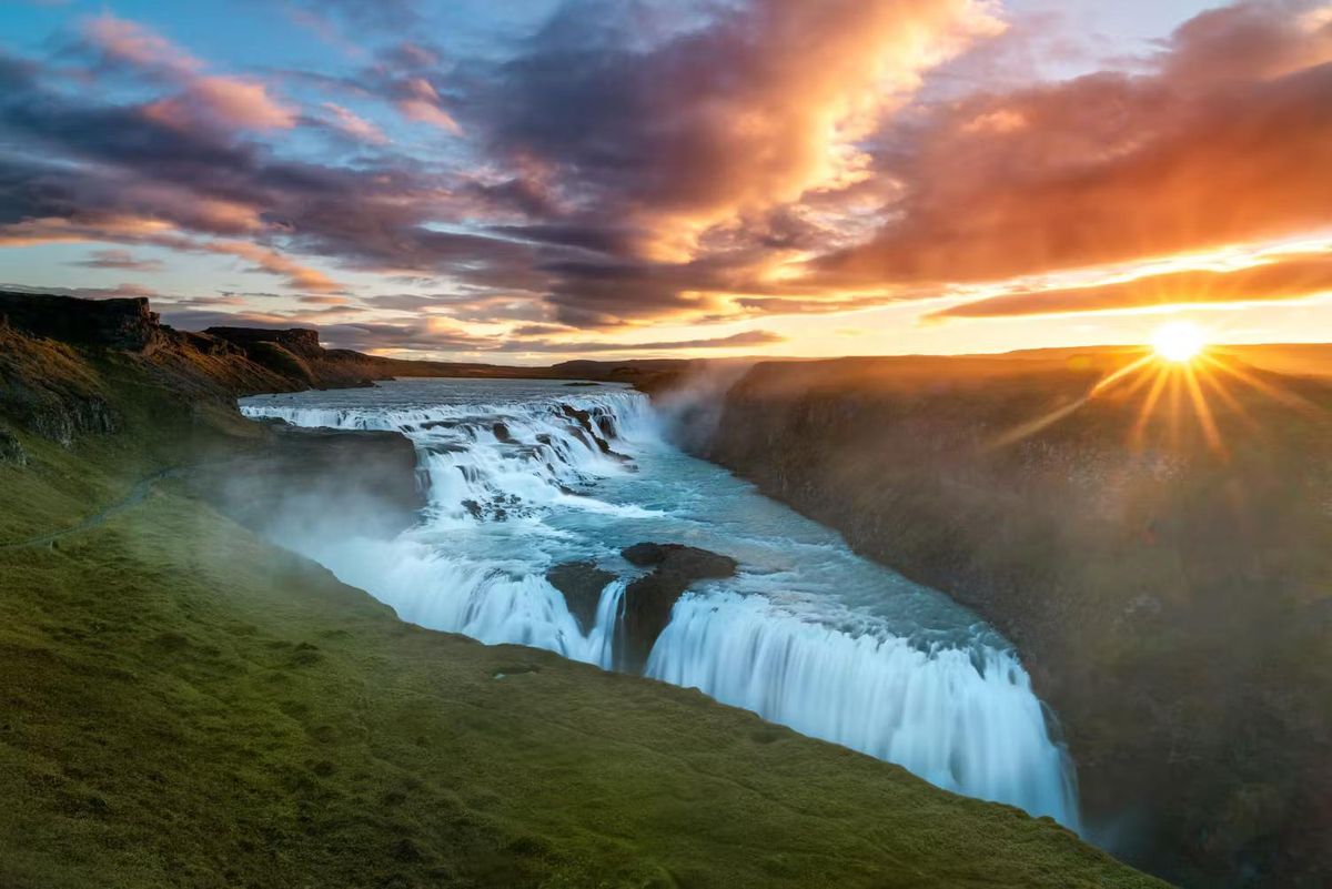 Gullfoss waterfall dropping into its canyon under a dramatic orange sunset