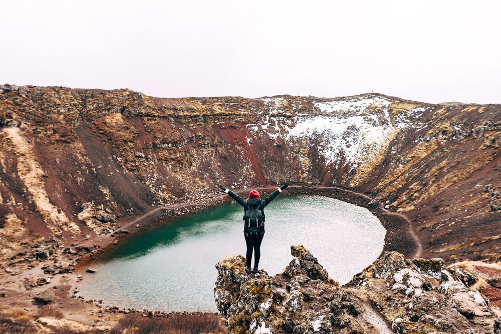 A girl stands on a cliff above Lake Kerid