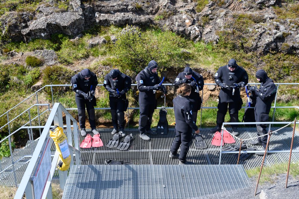 Group of tourist divers in wetsuits undergo training before diving in Silfra fissure