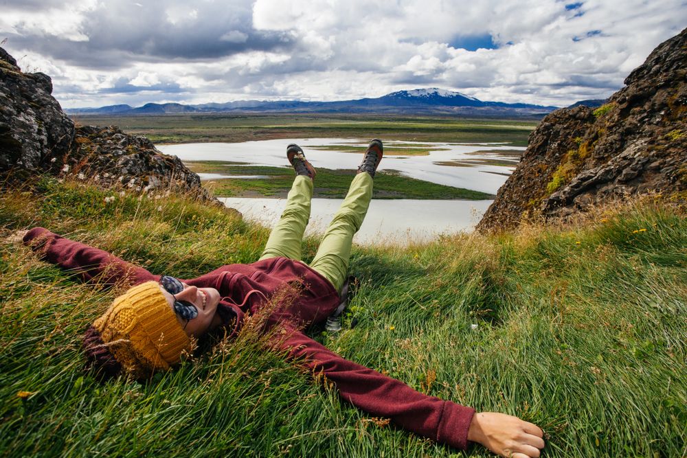 Happy young woman in bright clothes traveling Iceland, enjouing nature