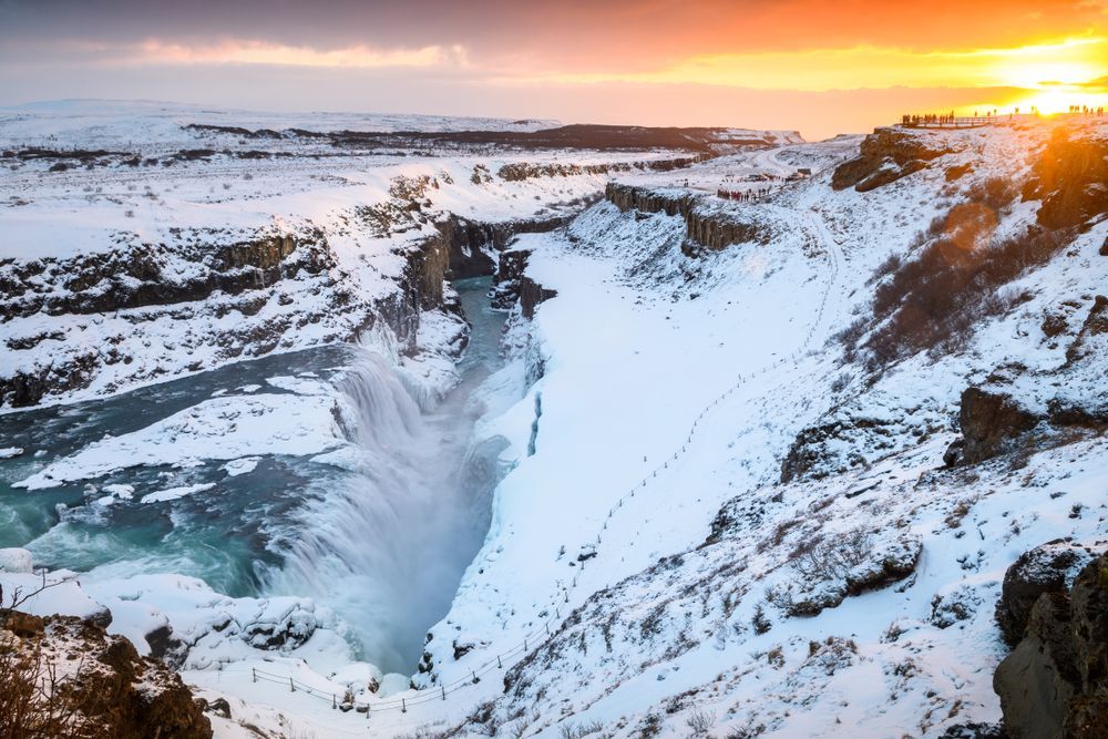 Gullfoss in winter at sunset with visitors on the viewing platform