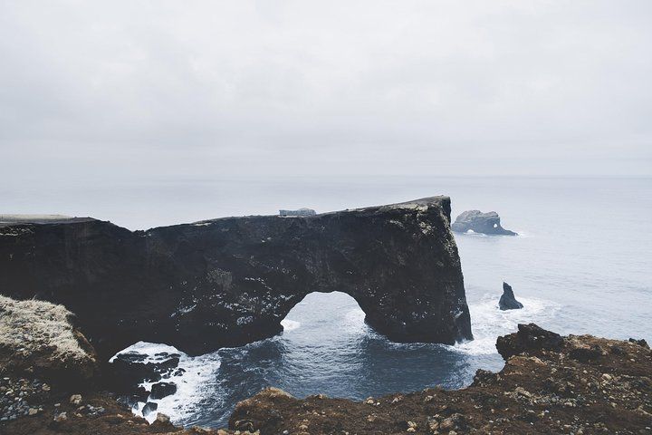 The rock arch at Dyrhólaey with waves breaking below and a small sea stack offshore