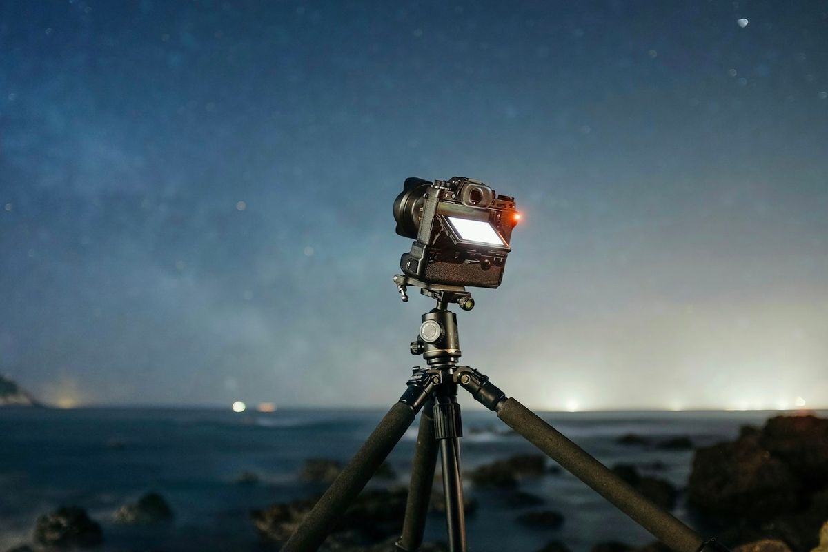 A camera on a tripod set up to photograph the night sky on a long exposure