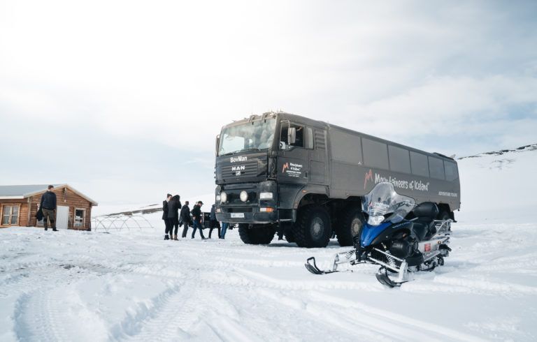 A glacier vehicle and snowmobiles on the ice