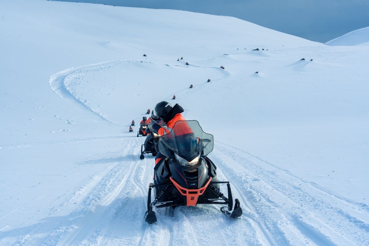 Group of tourist riding snowmobile through snow covered mountain glacier during winter in Iceland