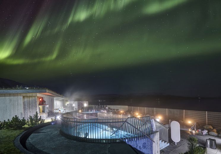 The Fontana geothermal baths at night with green northern lights overhead