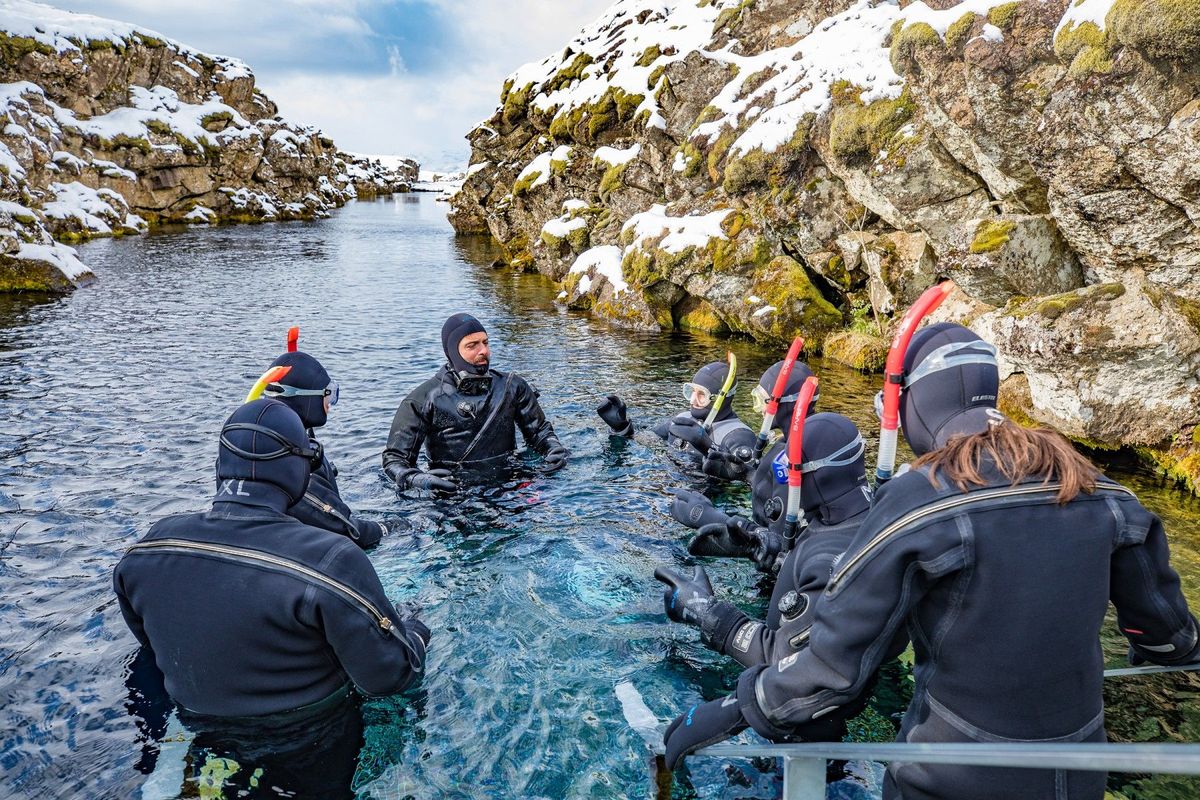 A snorkelling group entering the water at Silfra in snow