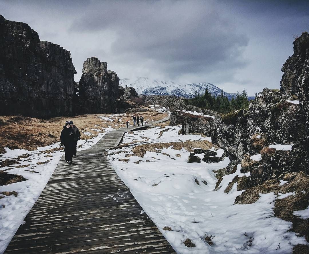 Visitors walking a snow-covered boardwalk at Þingvellir in winter