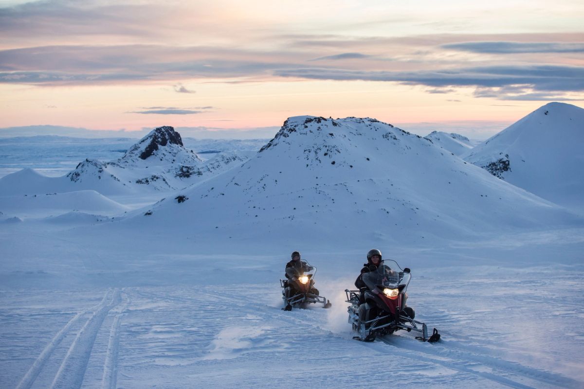 Snowmobiles on the glacier with low sun behind the riders