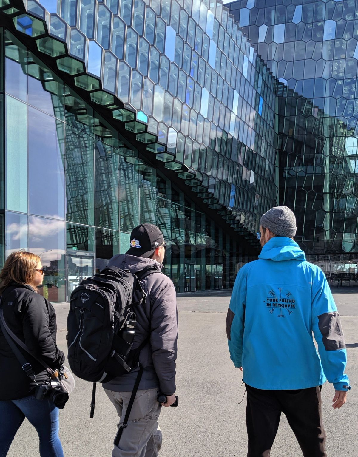 Visitors walking past the glass facade of Harpa concert hall