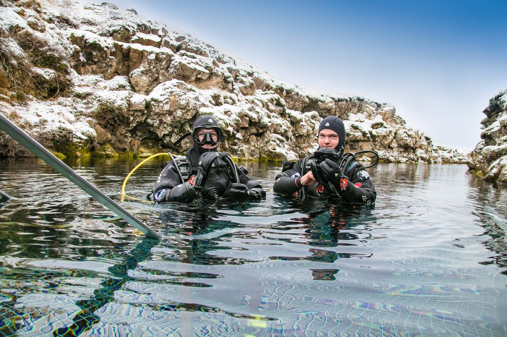 Scuba divers preparing entering in the water at Silfra rift