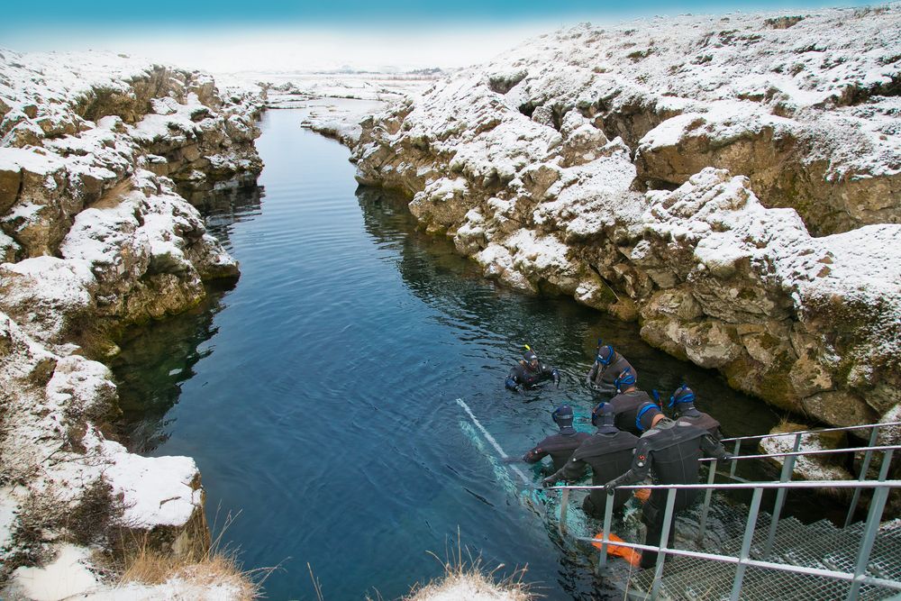 Scuba divers preparing entering in the water at Silfra rift