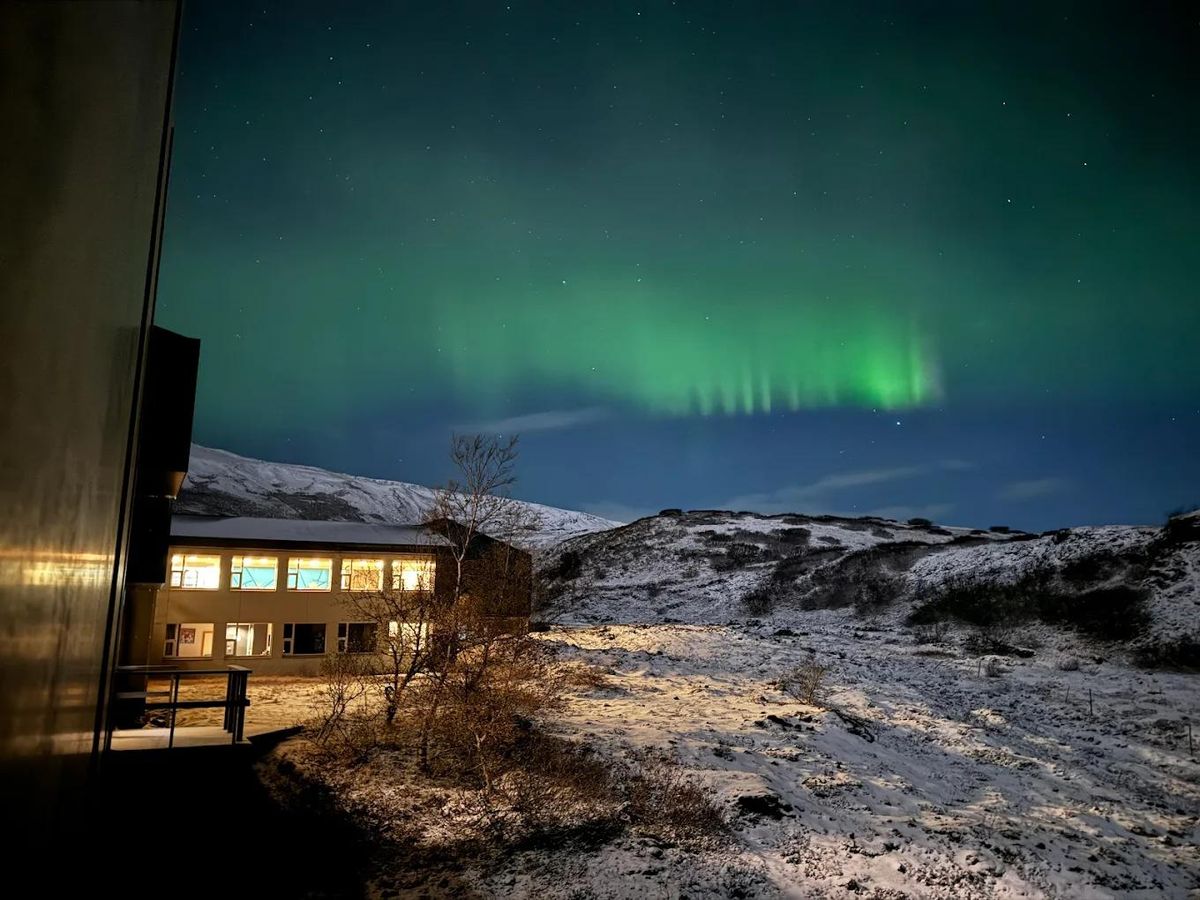 The northern lights above a snowy landscape with a lit building