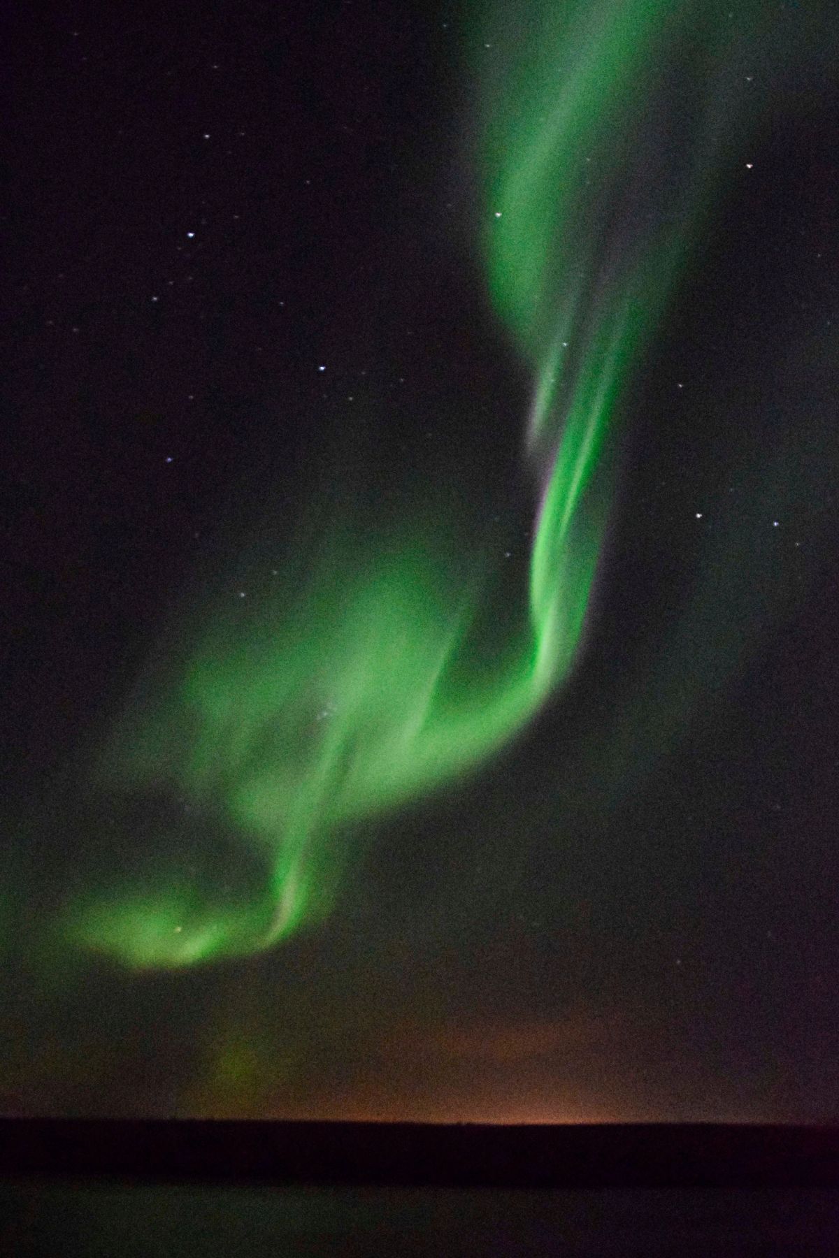 A green aurora ribbon low over the horizon