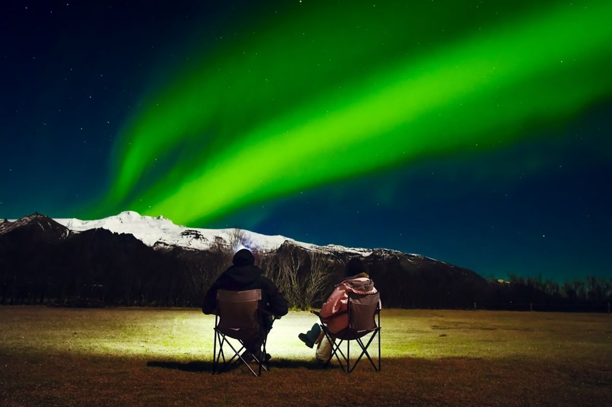 Woman and man at winter night landscape in Iceland