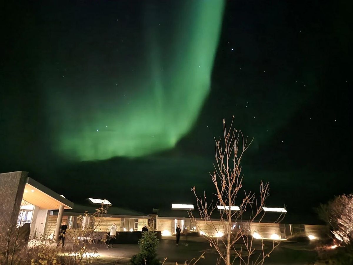 The northern lights above a lodge with guests watching