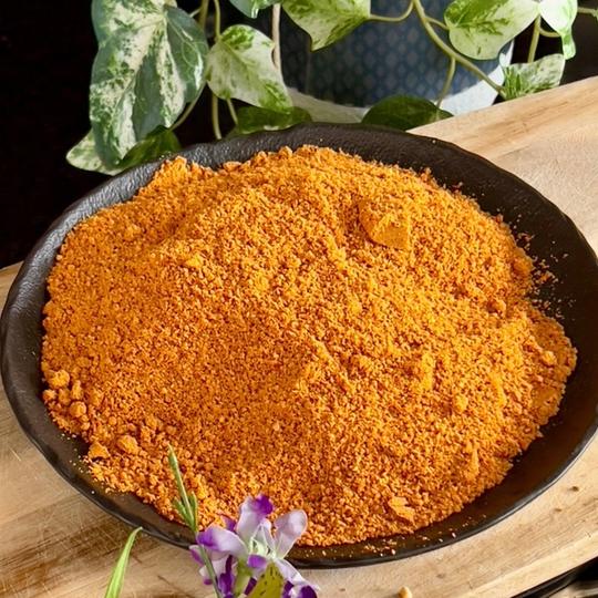 Idli milagai podi, a coarse orange spice powder, in a black bowl