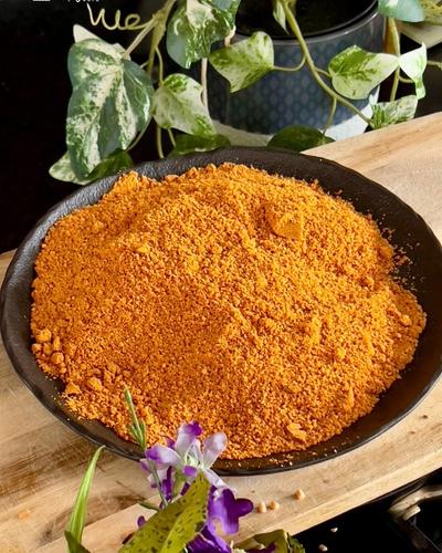 Idli milagai podi, a coarse orange spice powder, in a black bowl