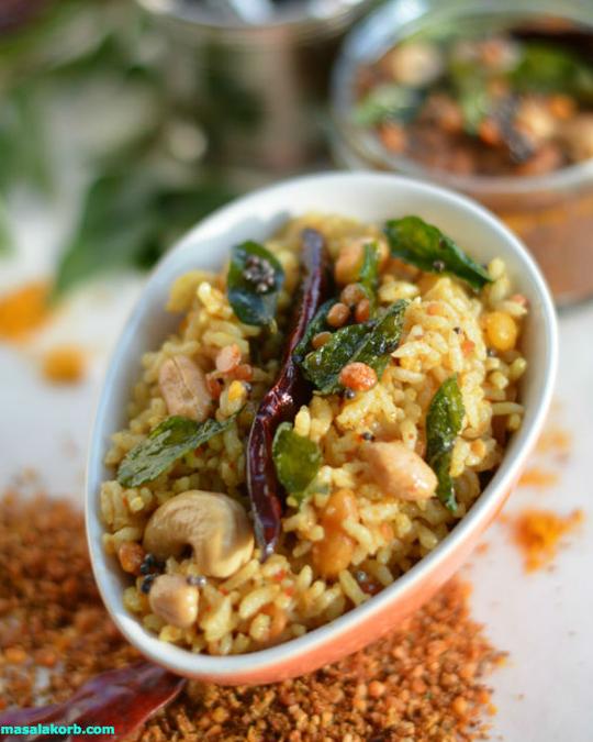 Tamarind rice with peanuts, cashews, a dry red chilli and curry leaves in a white bowl
