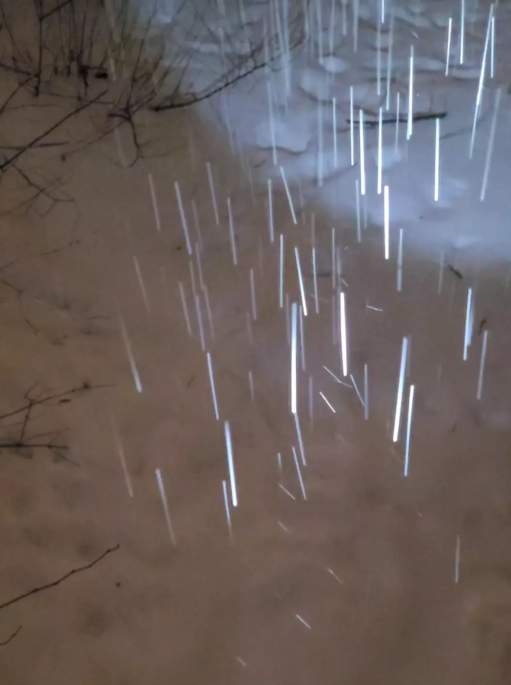 Falling snow causes spark-like reflections, illuminated by flashlight