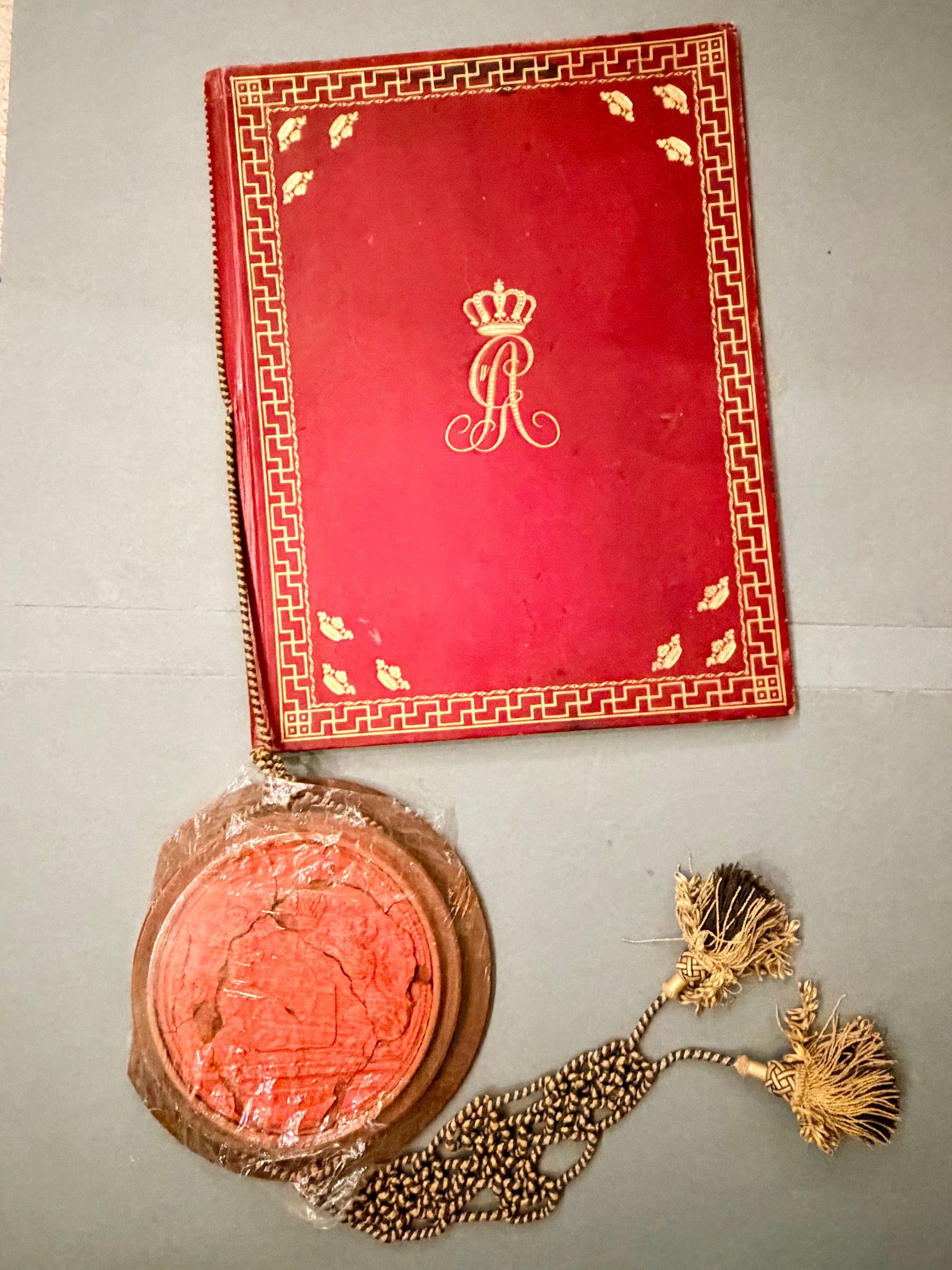 Rött originalomslag till Brauners friherrebrev från 1801, med förgyllt kungligt monogram och dekorativ bård. Nedanför ligger det röda sigillet med snören.