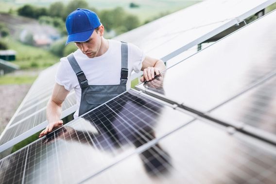 En mann med caps og snekkerbukse som installerer solcellepanel