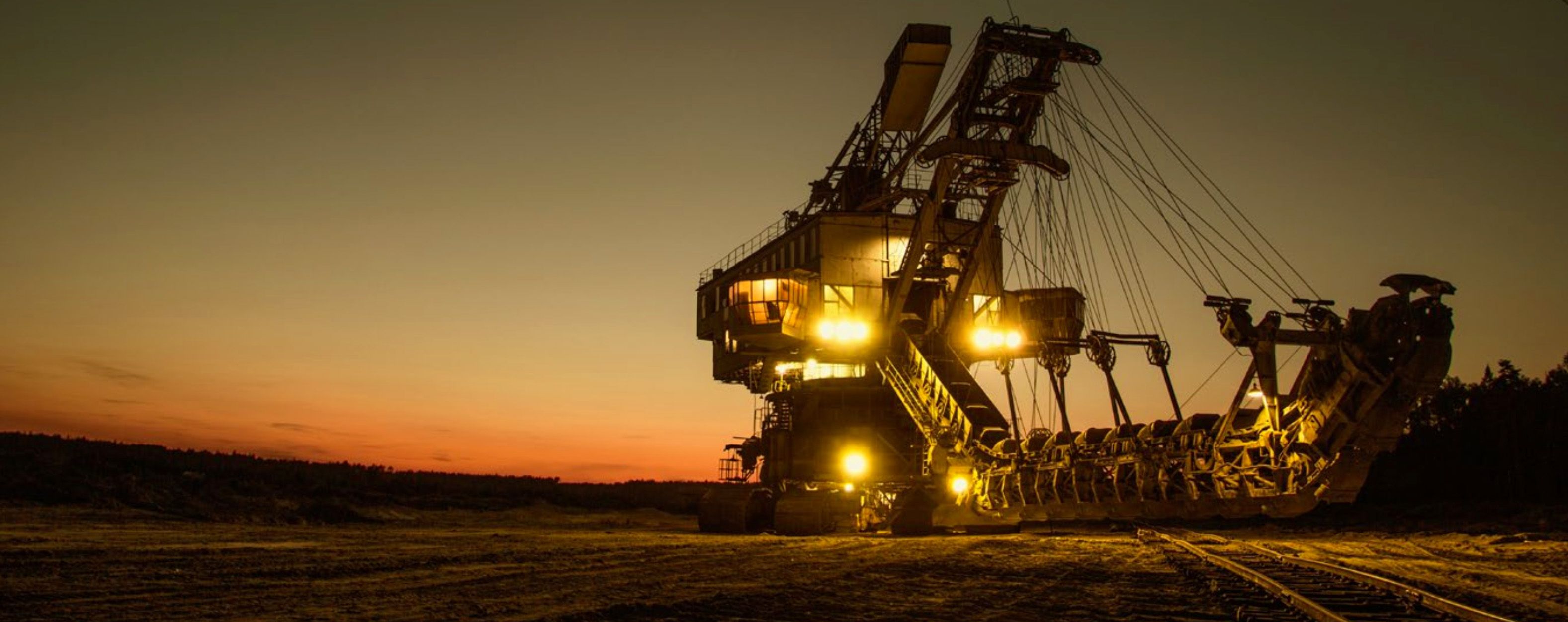 Large automated mine site machinery as sunset