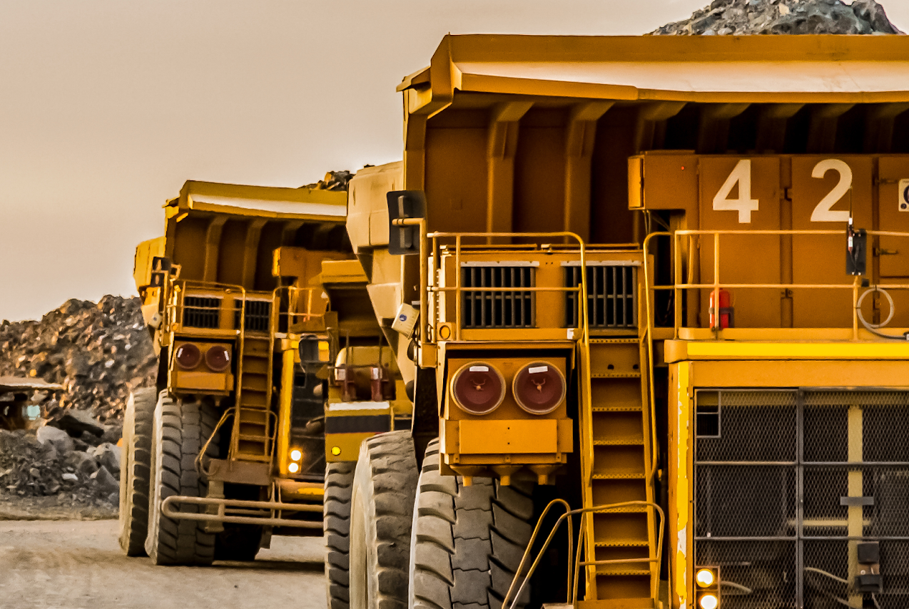 Yellow trucks in mining pit carrying rocks