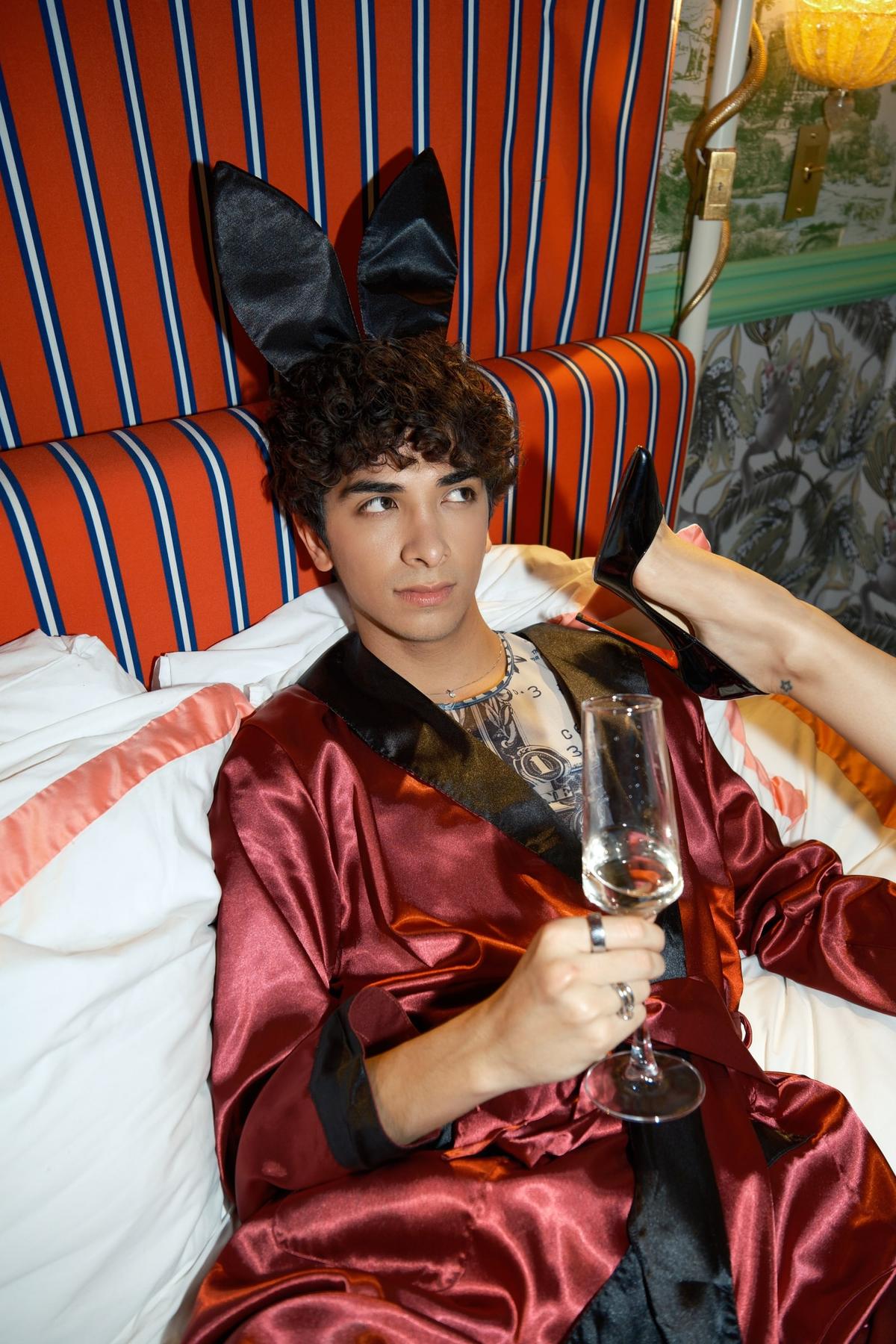 Joseph in a red satin robe and black bunny ears, holding a champagne flute