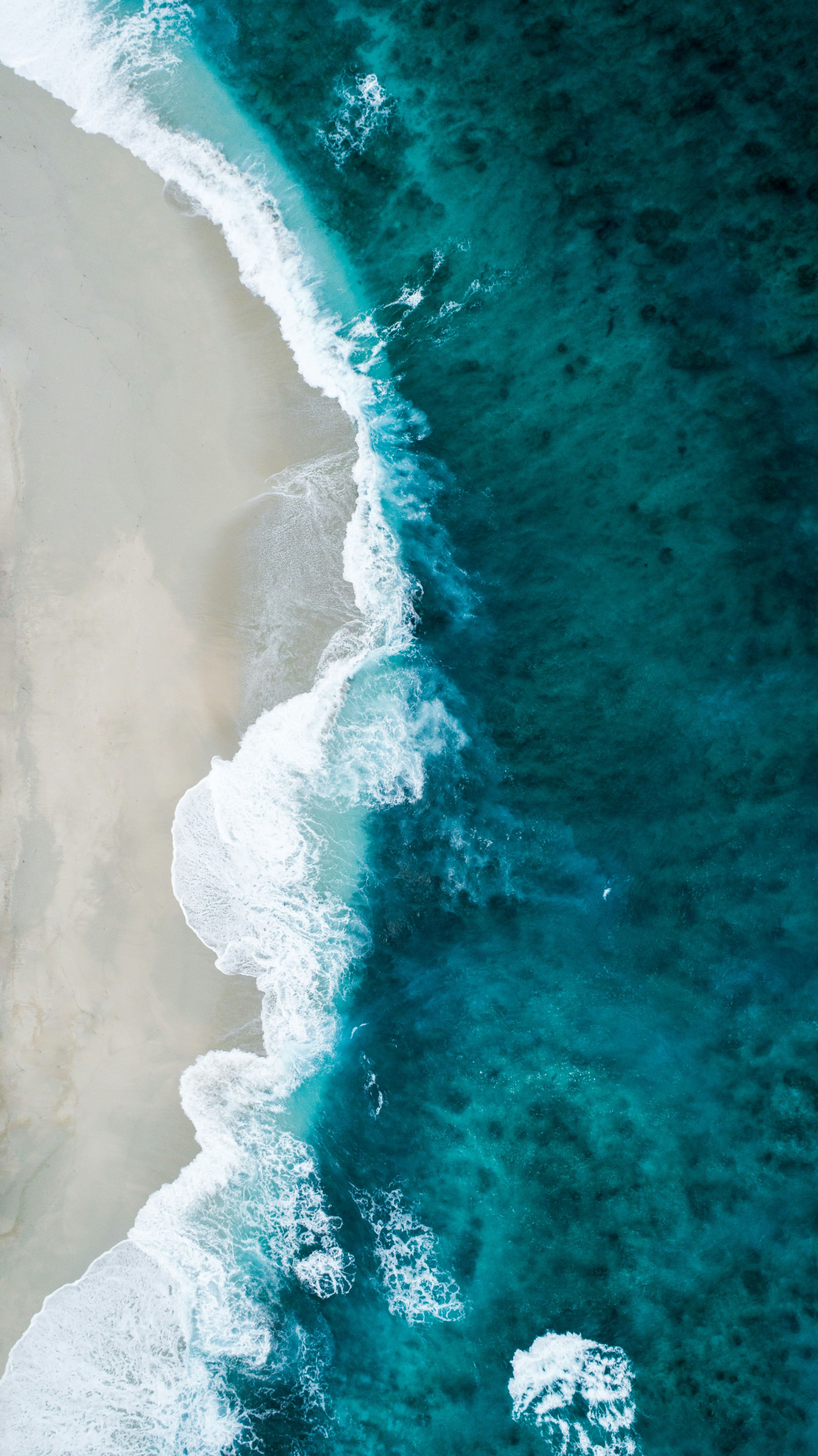 Waves breaking on a sandy beach, seen from above