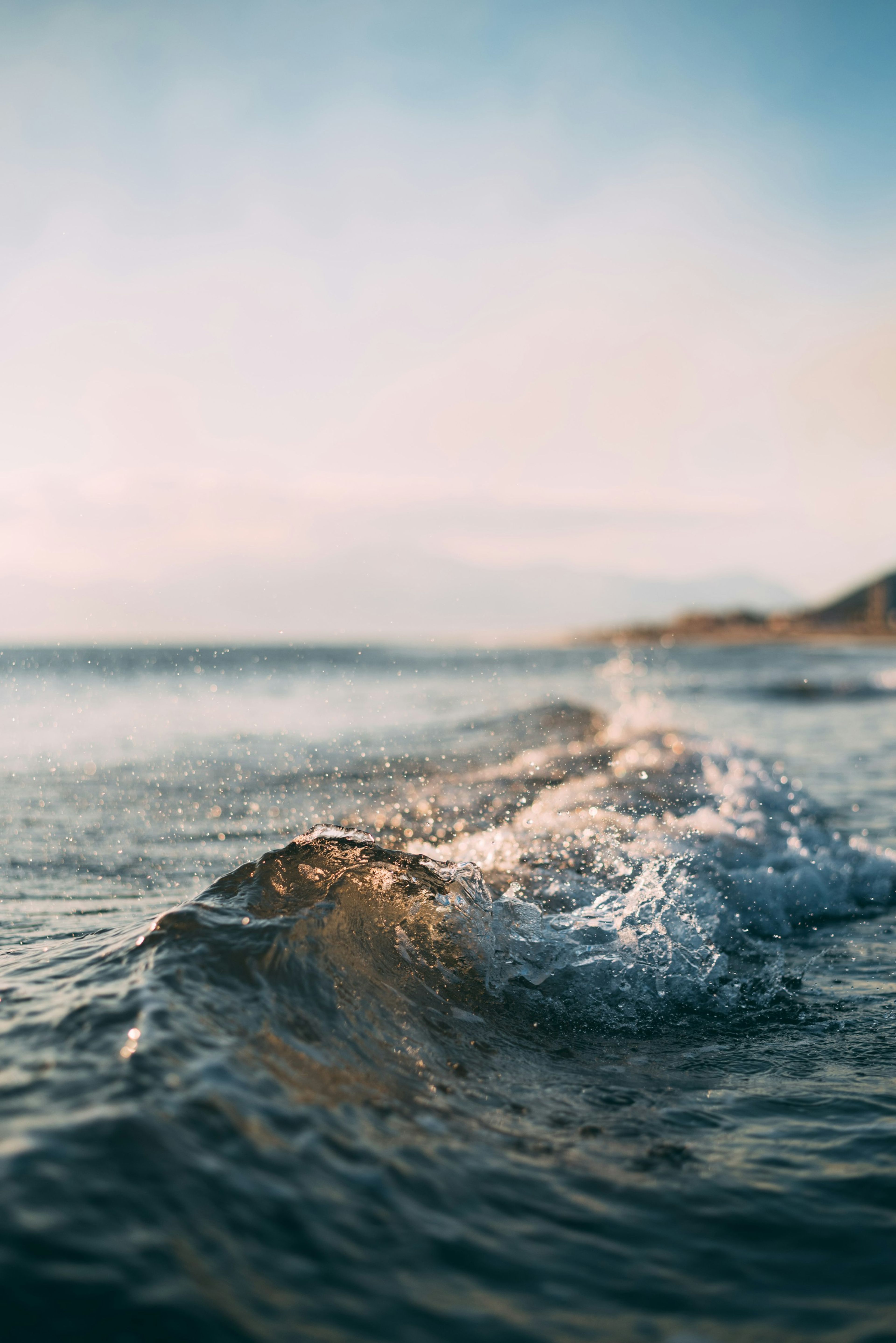 Waves rolling onto a quiet beach under a pale sky