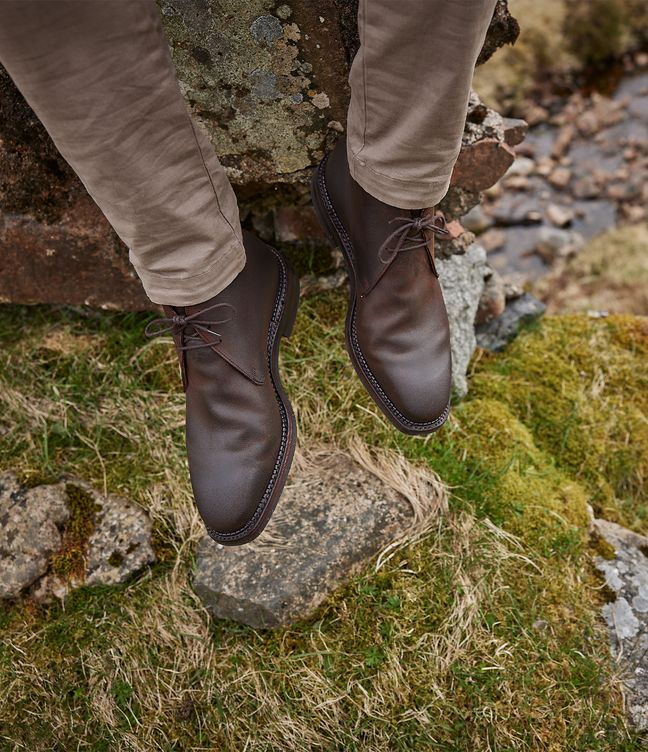 Man wearing Crockett & Jones’s Dark Brown Rough-Out Suede chukka boot out in the countryside hills