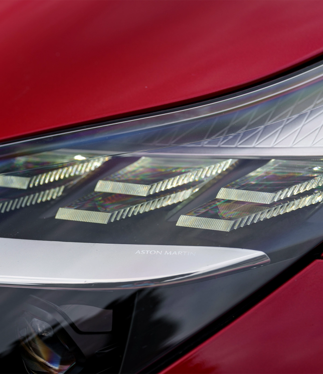 Headlights of a red Aston Martin DB12