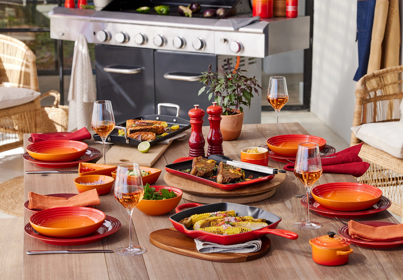 Table set with a mix of Volcanic Orange and Cerise Red Le Creuset Cookware