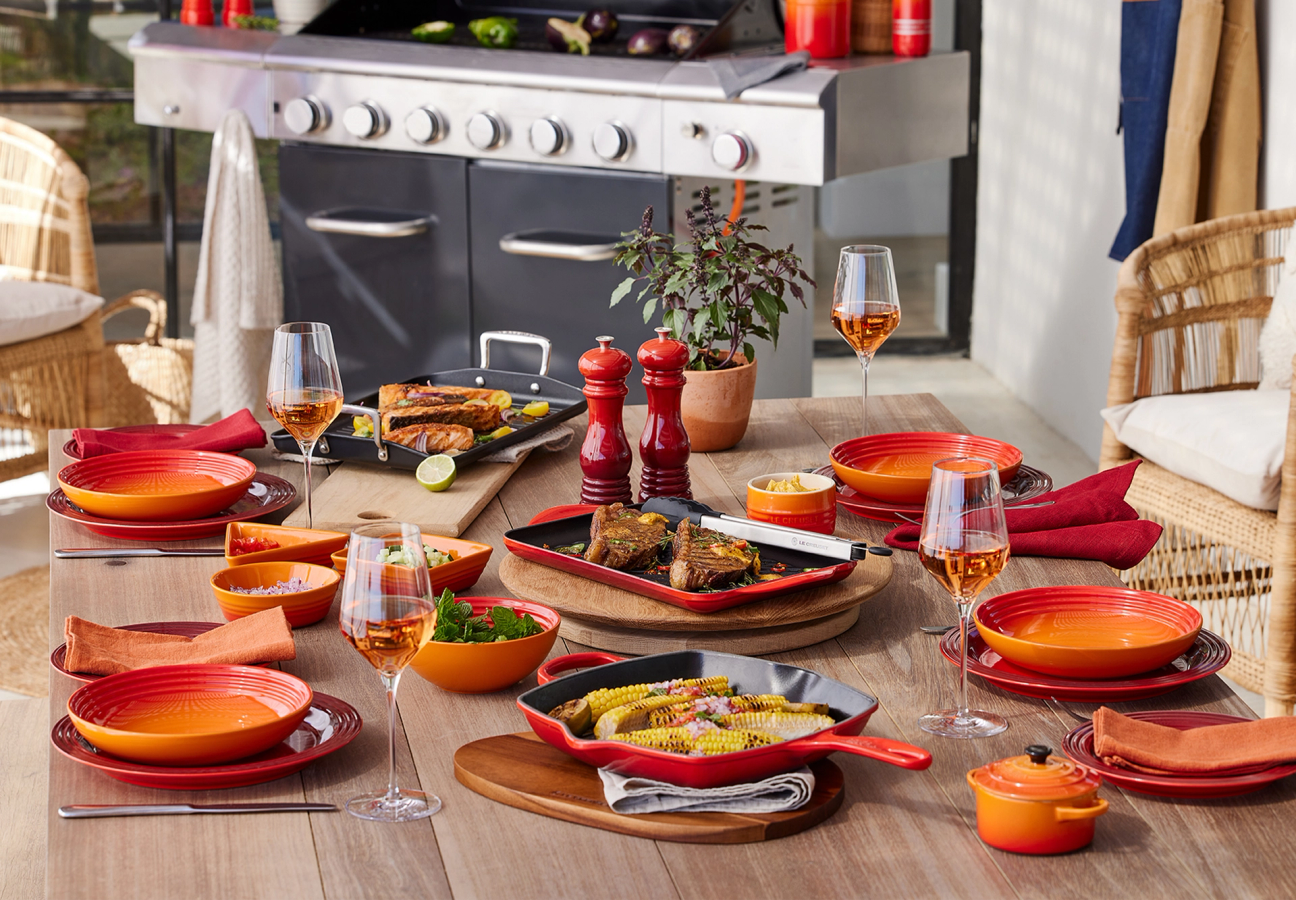 Table set with a mix of Volcanic Orange and Cerise Red Le Creuset Cookware
