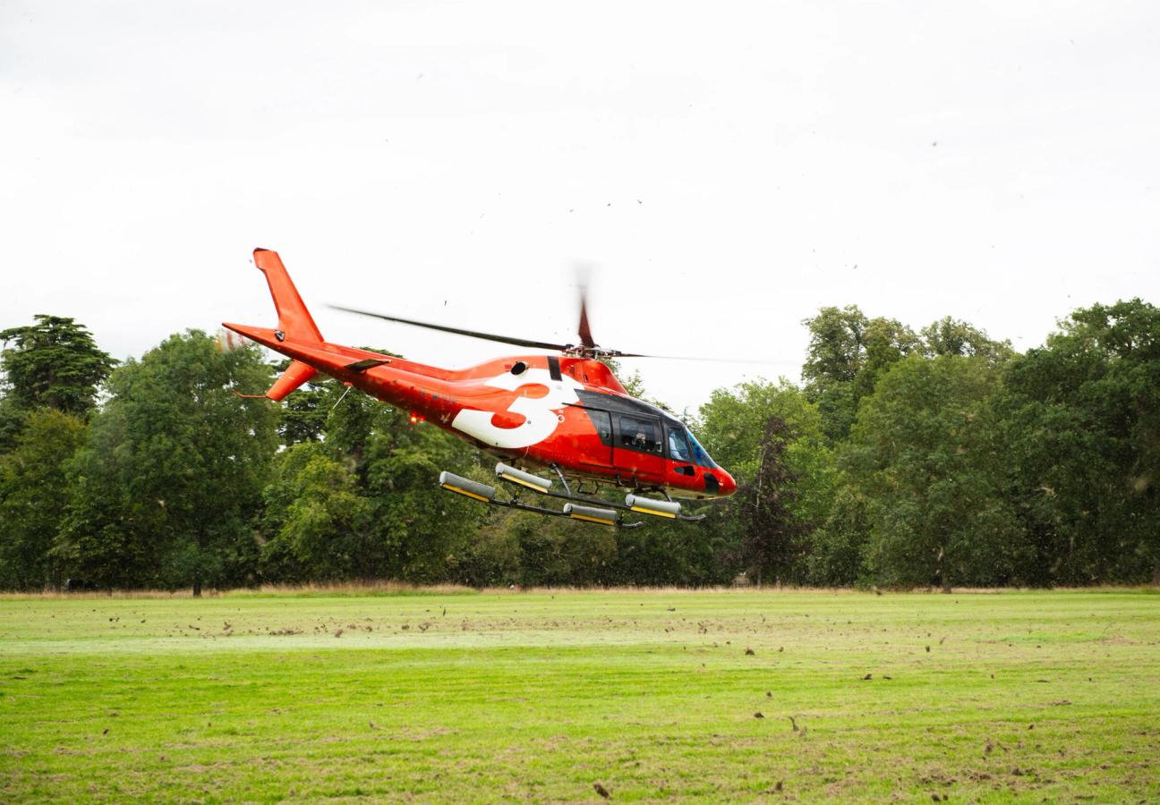 Red Helicopter coming in to land on grass