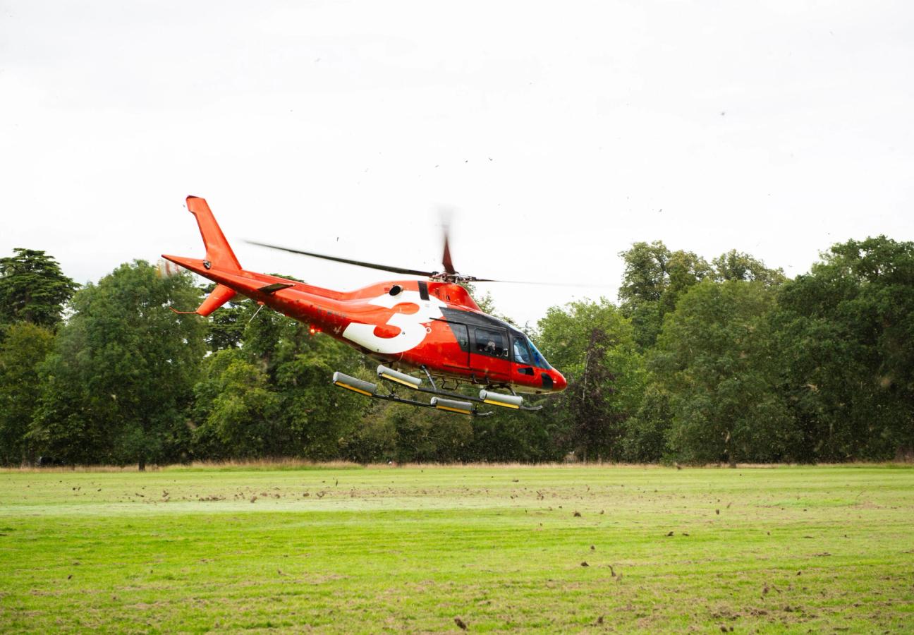 Red Helicopter coming in to land on grass