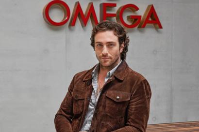 Aaron Taylor-Johnson stands in front of Omega sign at the watchmaker's Swiss headquarters