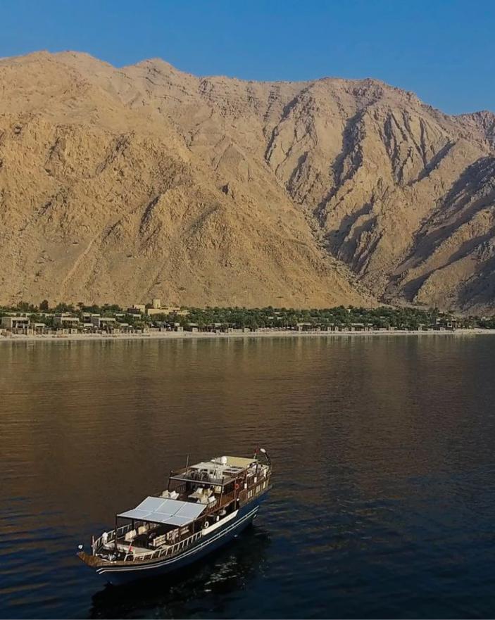 Boat on the water beside the mountains at Zighy Bay