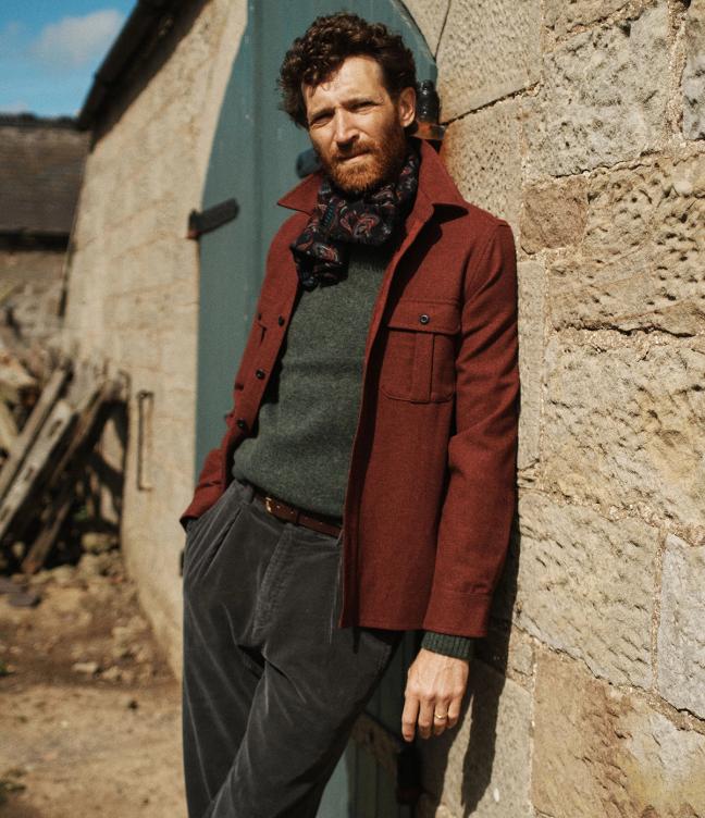 Man wearing Burgundy Aubin Jacket leans again old brick wall