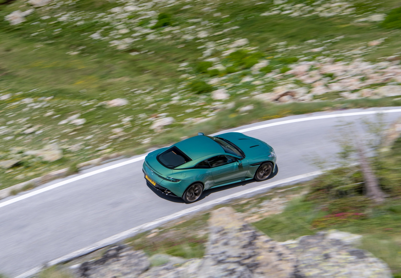 Green Aston Martin DB12 driving on the road