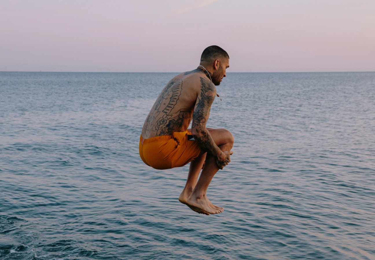 Tracksmith model, wearing swimshorts and diving into water