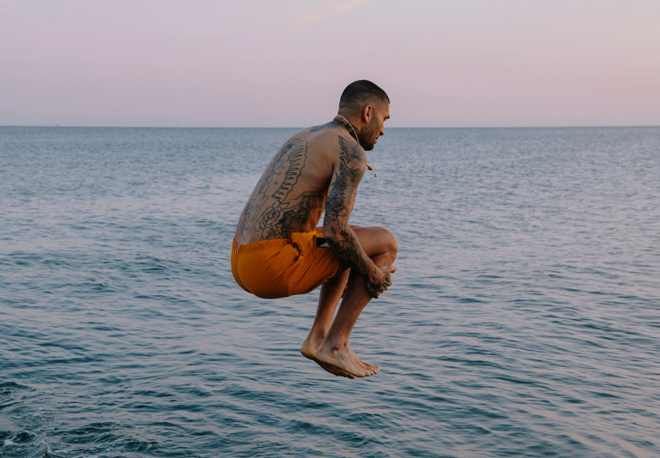 Tracksmith model, wearing swimshorts and diving into water