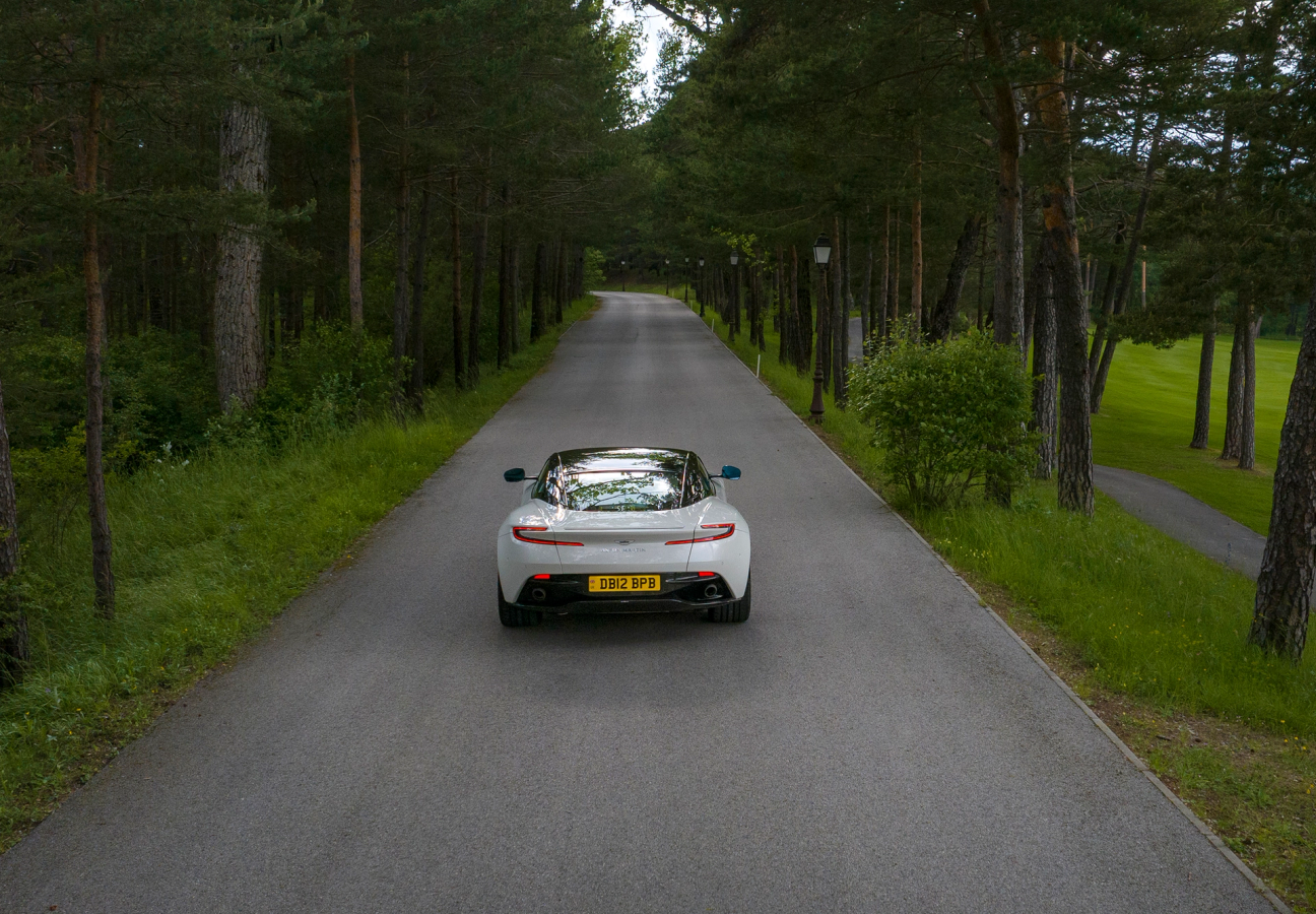 White Aston Martin DB12 driving on the road